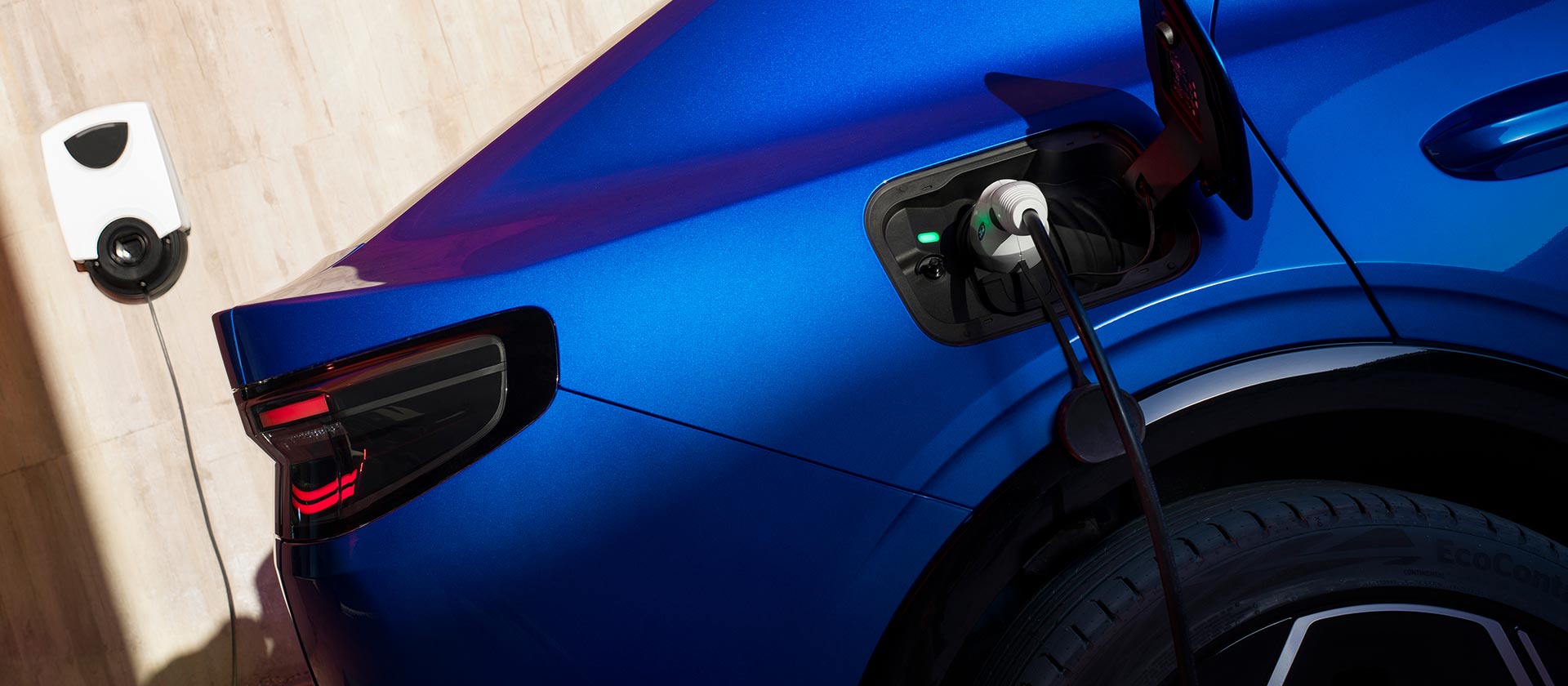 Close-up of the electric Ford Capri® charger port, plugged into an wallbox EV charger.