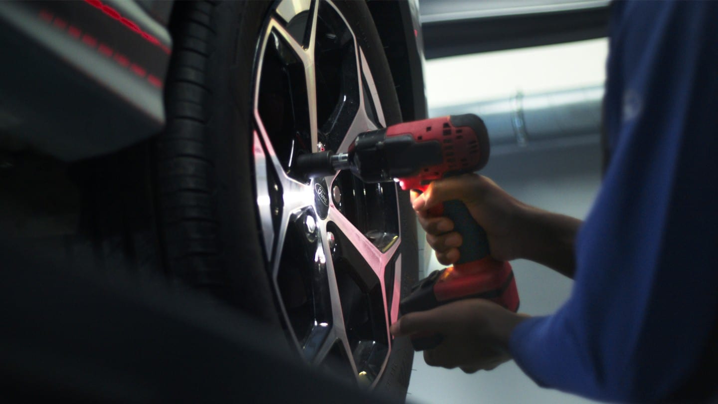 A Ford technician uses a power tool to change a tyre in a Ford service centre.